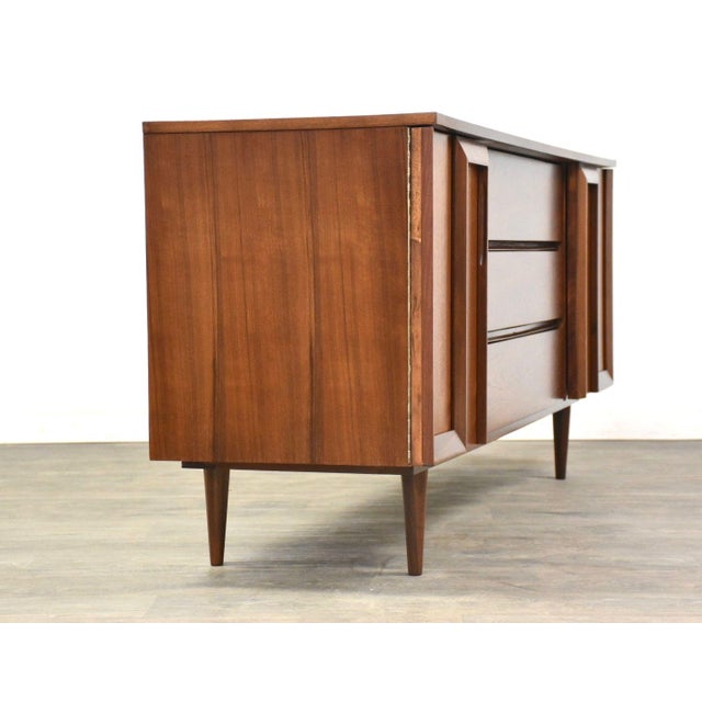 A mid century modern walnut nine drawer dresser with two doors and sculpted details. Professionally refinished. 72.25”...