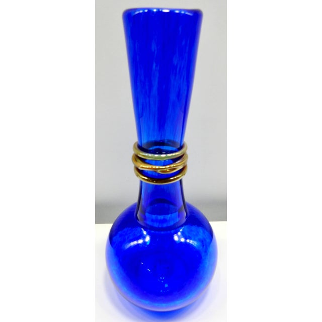 Vibrant cobalt blue forms this handblown vase by Ingris of Chattanooga, Tennessee. An iridescent rope is twined around the...