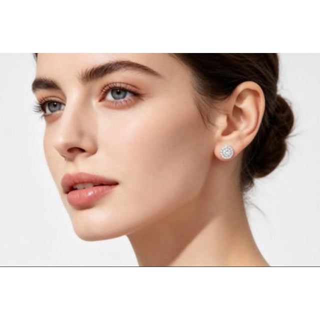 Elegant 14K white gold stud earrings featuring a solitaire diamond surrounded by brilliant round diamonds, totaling 1...