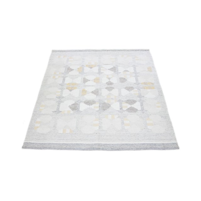 The flatweave rug showcases a contemporary Swedish design with a subtle gray base. It features an elaborate geometric...