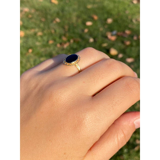 The 49th Avenue: Onyx Flower Ring in Yellow Gold. This ring features a central oval buff top black onyx, skillfully bezel-...
