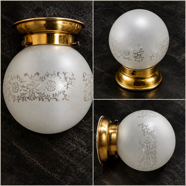 This ceiling light fixture features a frosted glass shade with an etched floral design and a brass metal mounting base. A...