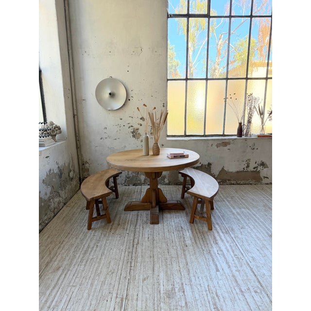 A set comprising a round solid oak table and two rounded pine benches, perfectly complementing the table. Dating from the...