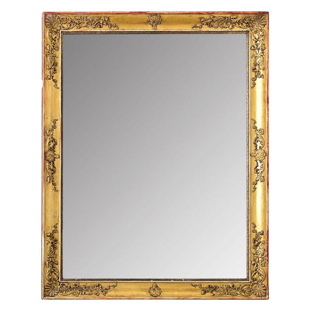 This French Empire mirror (c. 1800) is symmetrical to hang in either direction, exhibiting low-relief floral decorations...