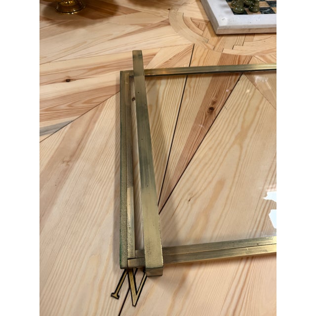Elegant rectangular serving tray featuring a brass frame, clear glass base, and raised handles. The brass displays a warm...