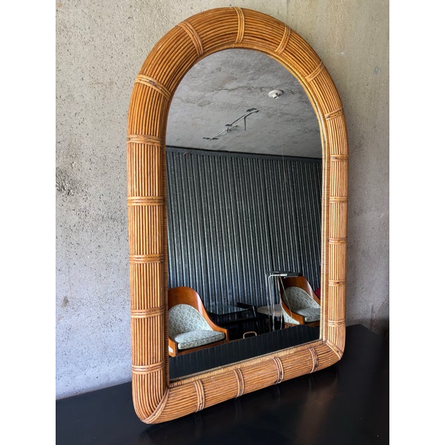 A beautifully crafted vintage pencil reed wall mirror featuring a timeless arched silhouette and finely wrapped reed...