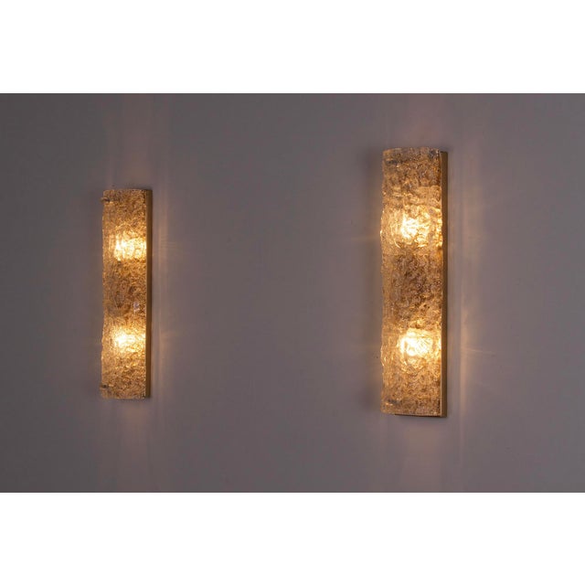 Pair of wall lights each made up of a half-cylinder in thick murano glass with a frosted texture. the glassware is...