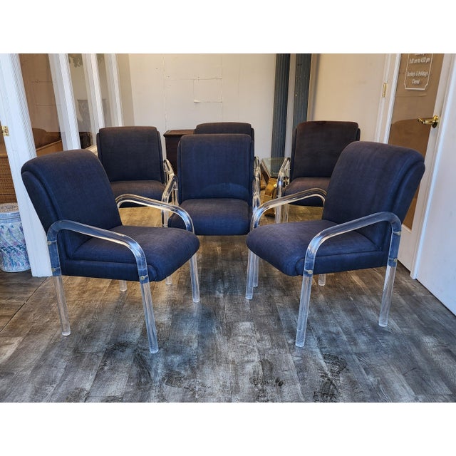 A beautiful set of six dining chairs with curved Lucite frames and brass detail. Chairs upholstered in original gray...