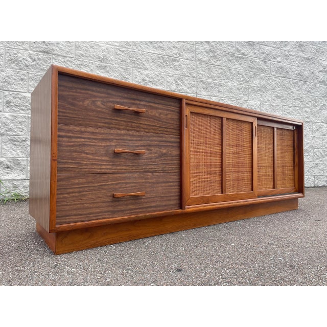 Credenza comes with three, smooth-sliding drawers affixed with carved wooden handles. Two cane front sliding doors open to...
