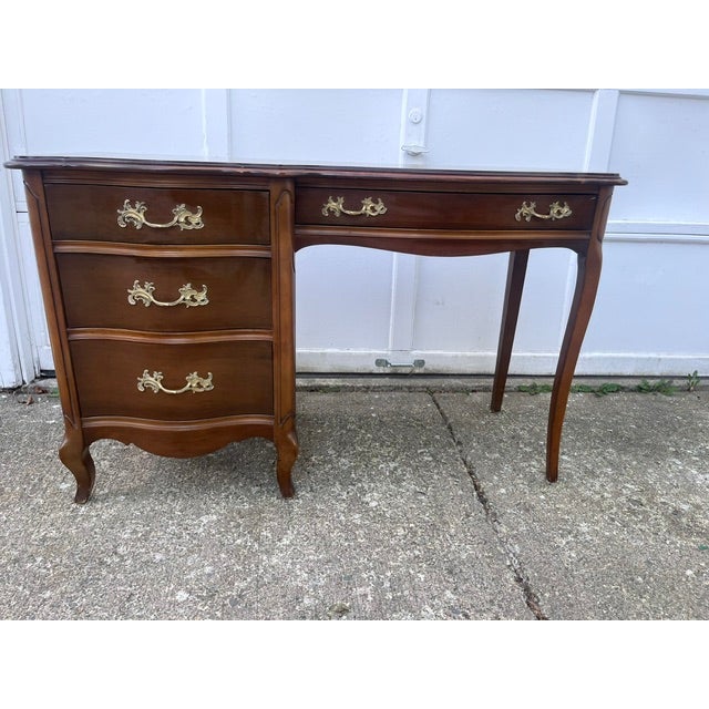 A distinctive asymmetrical design featuring a three-drawer pedestal on the left and a single long lap drawer beneath the...