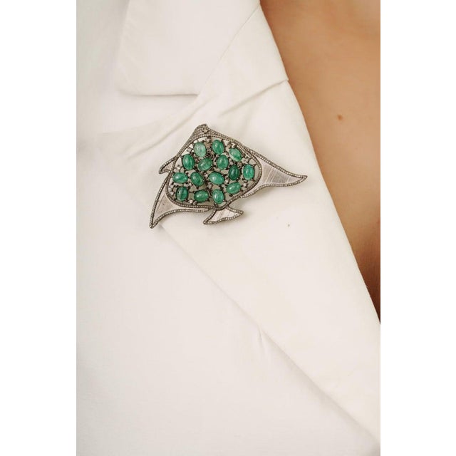 Crafted in 925 sterling silver, this striking manta ray brooch pendant showcases 12.75 carats of vibrant emeralds accented...