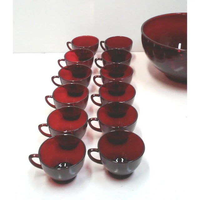 A fabulous ruby red glass punch bowl with twenty four matching punch cups. This 70’s era vintage punch set is a deep,...