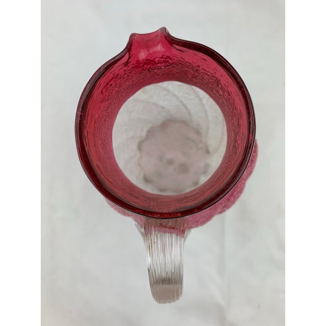 An enchanting rose-colored glass pitcher, with a softly faded blush hue. The body has gentle curves connected to a fluted...