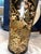 Elegant black decorative vase featuring intricate gold floral motifs. Subtle touches of purple and warm tan tones enhance...