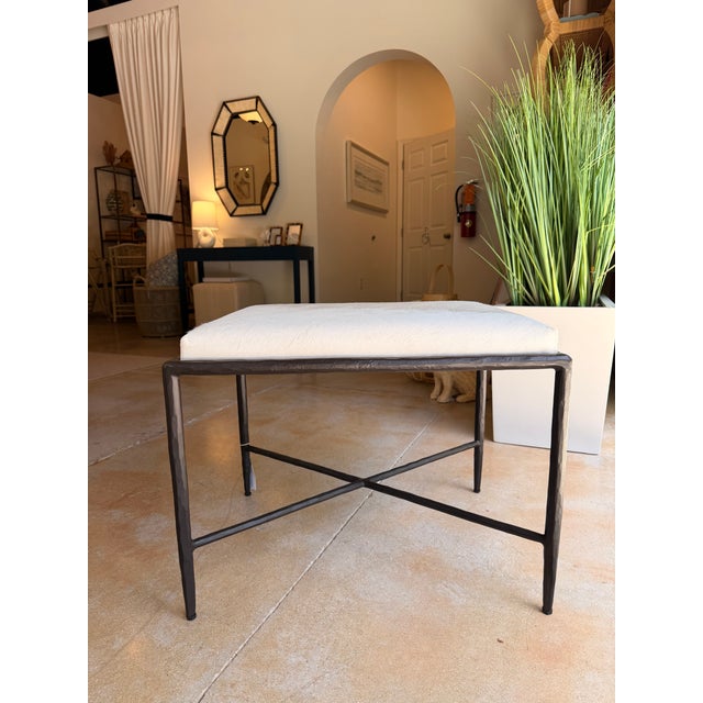 Contemporary ottoman featuring a white hair hide upholstered cushion atop a sleek black metal frame for a striking blend...