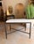 Contemporary ottoman featuring a white hair hide upholstered cushion atop a sleek black metal frame for a striking blend...