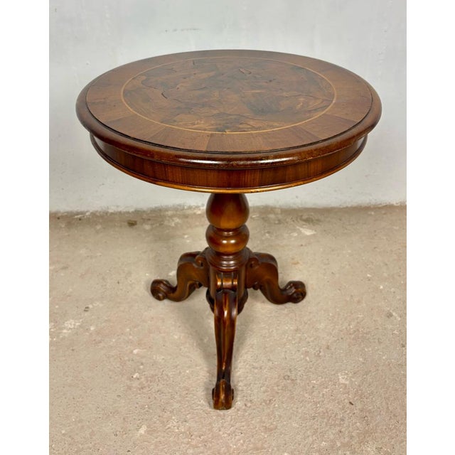Elegant round occasional table featuring a beautifully inlaid top and sculptural tripod base. The circular top displays...