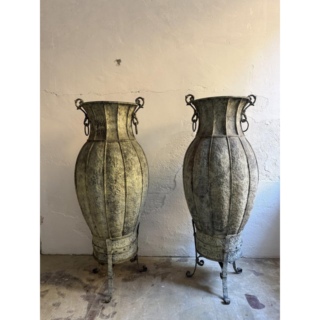 A pair of 20th-century ornamental amphorae. These large vases are made of hammered copper with vertical segments and have...