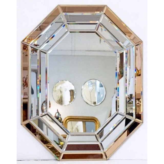 A beautiful Italian Modernist octagonal mirror featuring a segmented colored and beveled glass design surrounding a clear...