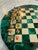 Elegant Italian chess set featuring a circular malachite stone board inlaid with alternating bone squares, showcasing the...