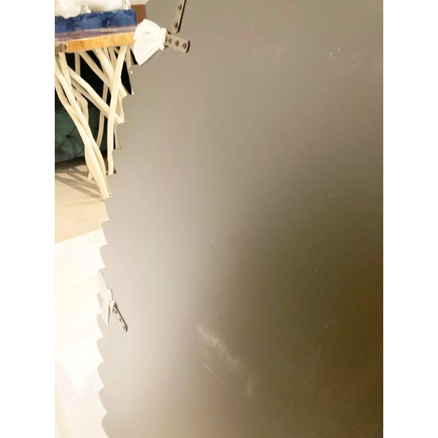 This oval wall mirror features a striking silhouette. The exaggerated oval shape is enhanced with a petal shaped purple...