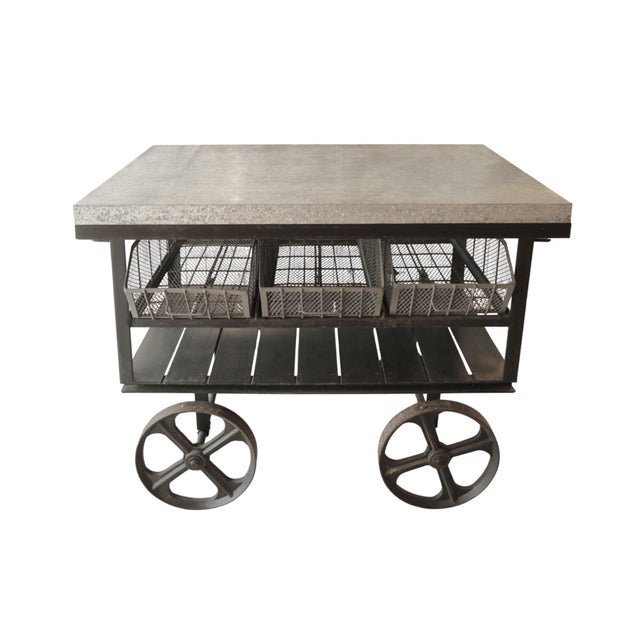 An industrial rolling work cart table, with a hand finished aluminum wrapped table top. Underneath are three wire bins...