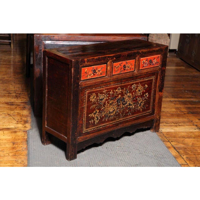 A Gansu painted sideboard with three-drawers over two doors delicately adorned with flowers from the early 20th century....