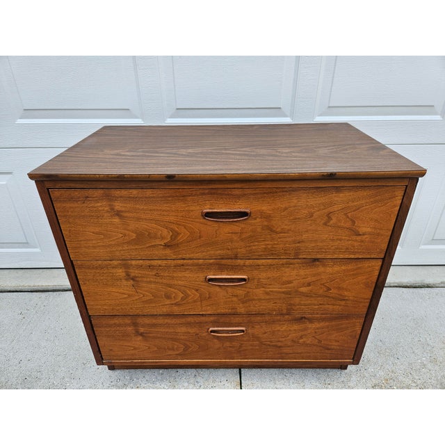 A classic Lane three drawer chest of drawers or dresser with walnut veneers and wooden drawer pulls. The top is laminate....