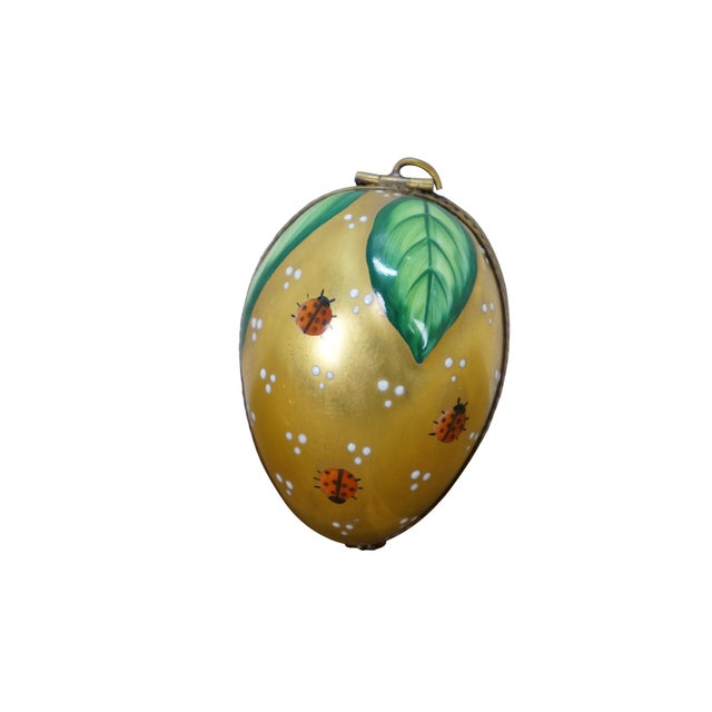 Late 20th century Limoges porcelain trinket / keepsake box in the shape of an egg, hand painted in gold with greens...
