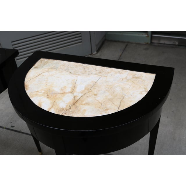 Pair of Ebonized Neoclassical Demi Lune Marble Top Consoles. Ebonized wood with marble tops and brass sabots.