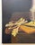 Still life painting on canvas of a tabletop with bread, cheese and beverage. Deep moody black background accentuates...
