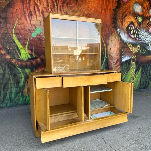 This is a Heywood-Wakefield two-piece, maple credenza or buffet finished in “wheat.” The top features sliding glass doors...