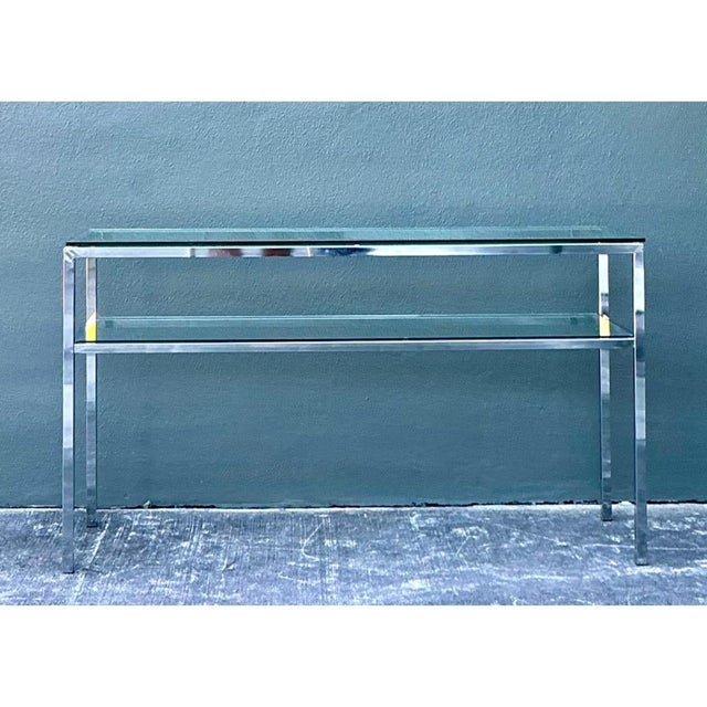 This vintage chrome and glass console table has the clean lines and restrained profile of mid-century modern design. A...