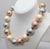 1985 goldtone big alternating tan mabe, grey and pink faux-pearls necklace with hook clasp. Marked "Monet" on one side and...