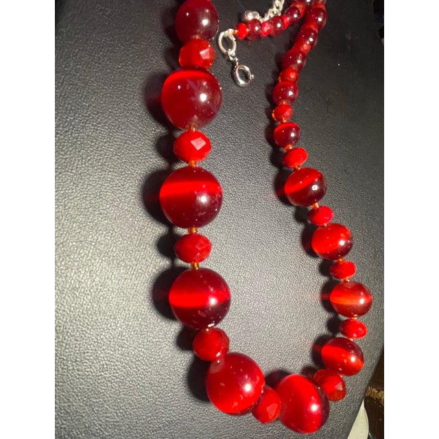 MCM necklace features graduated, vibrant red cats eye lucite beads interspersed with cherry red faceted glass. The larger...