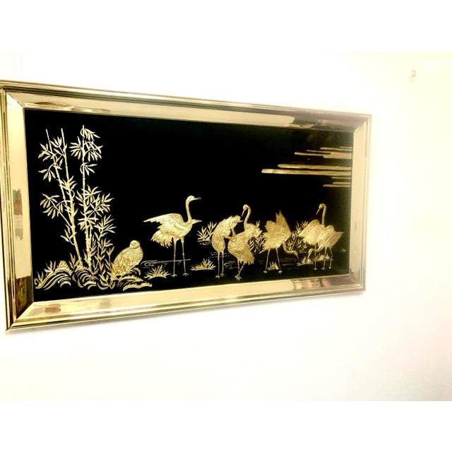 Large, elegant, framed black glass is etched with gold tone metal applique to create a serene scene of golden herons,...