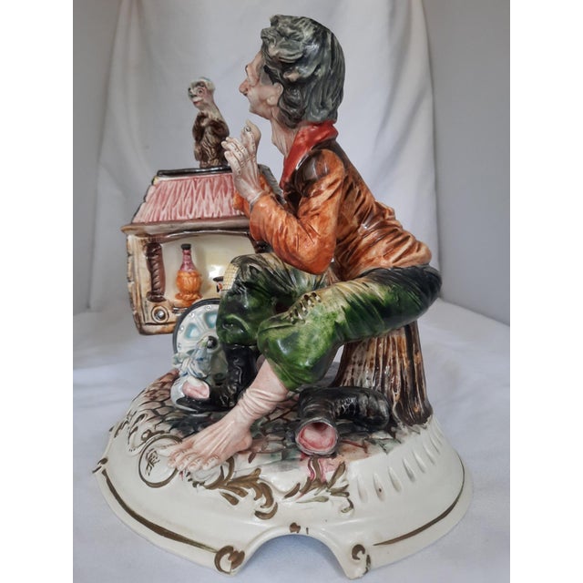A fine, highly detailed vintage hand-painted Italian polychrome porcelain figurine depicting a street organ grinder with...