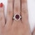 GIA Certified 5.52-carat oval-cut purplish red rubellite tourmaline framed by a halo of round-cut white diamonds, with a...