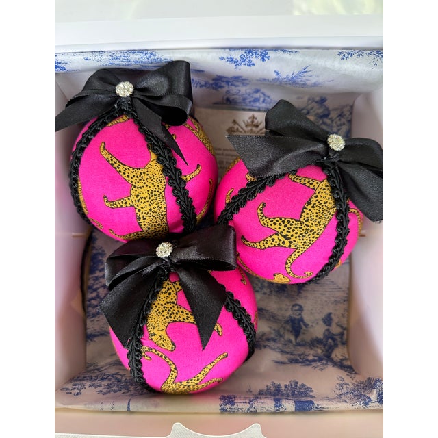 Bold leopard meets vibrant hot pink in this playful pair of handmade ornaments. Crafted from patterned cotton, the graphic...