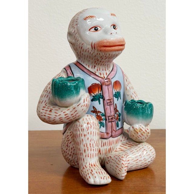 Fabulous vintage porcelain seated monkey holding a lotus in each hand. Each bloom is a candleholder for one taper...