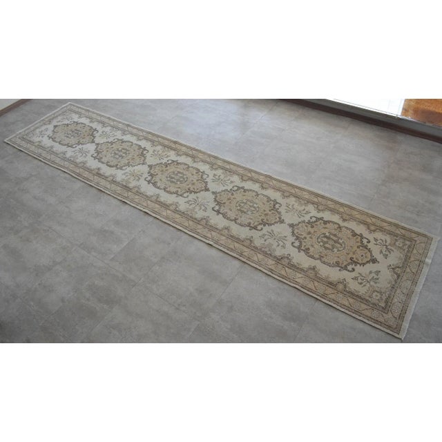 Vintage 1960s distressed Turkish Oushak rug runner. With beige field and shades of brown, ivory and tan throughout....