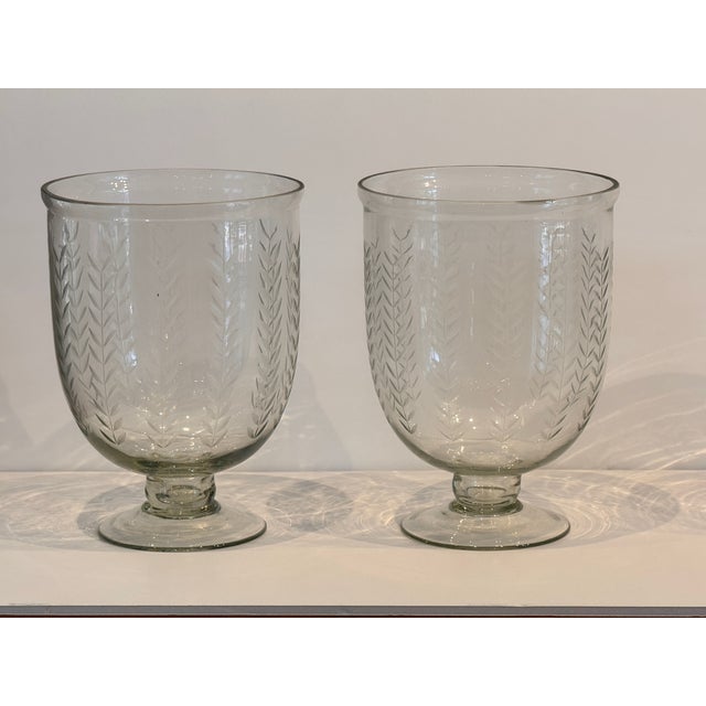 Pair of clear glass vases etched with a repeating wheat motif. Each has a rounded form that tapers to a simple circular...