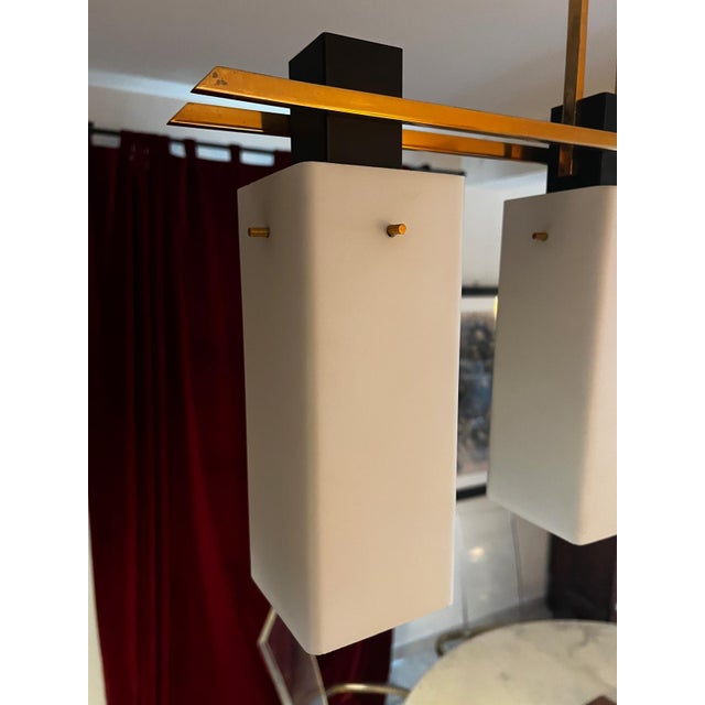 Three-light pendant lamp in opaline glass, brass, and iron, Maison Arlus, circa 1950. The opaline glass shades are in...