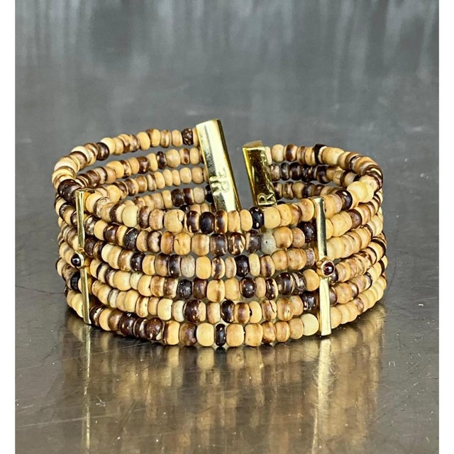 This vintage cuff bracelet is composed of multiple strands of small, rondelle-shaped coconut shell beads, strung in dense...
