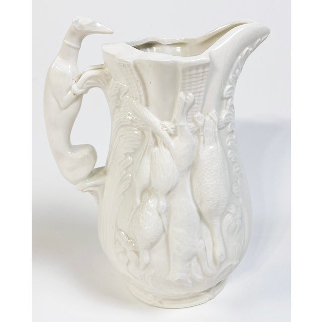 Rich ivory glazed pitcher in the style of Majolica. This whimsical piece features an intricately detailed hunting motif...