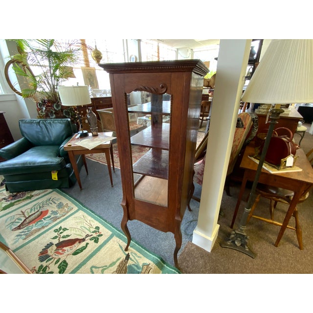 20th century Oak Victorian glass display cabinet. Carved and brass detail, bead trim. Long cabriole legs. Glass door is in...