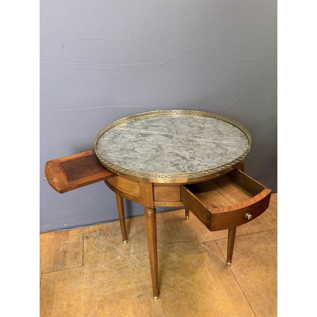A late 19th-century Directoire bouillotte table in cherry wood. It features two drawers and rests on four turned legs...