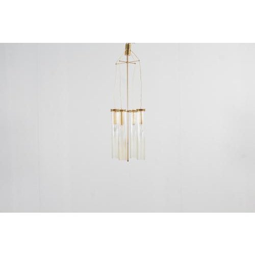 Beautiful four-light pendant lamp with golden brass structure and supports and cylindrical glass diffusers with irregular...