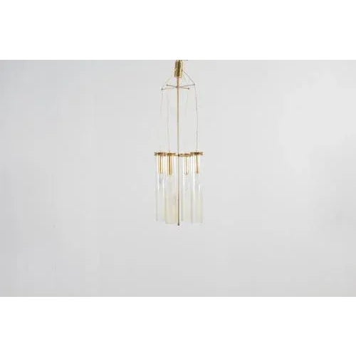 Beautiful four-light pendant lamp with golden brass structure and supports and cylindrical glass diffusers with irregular...
