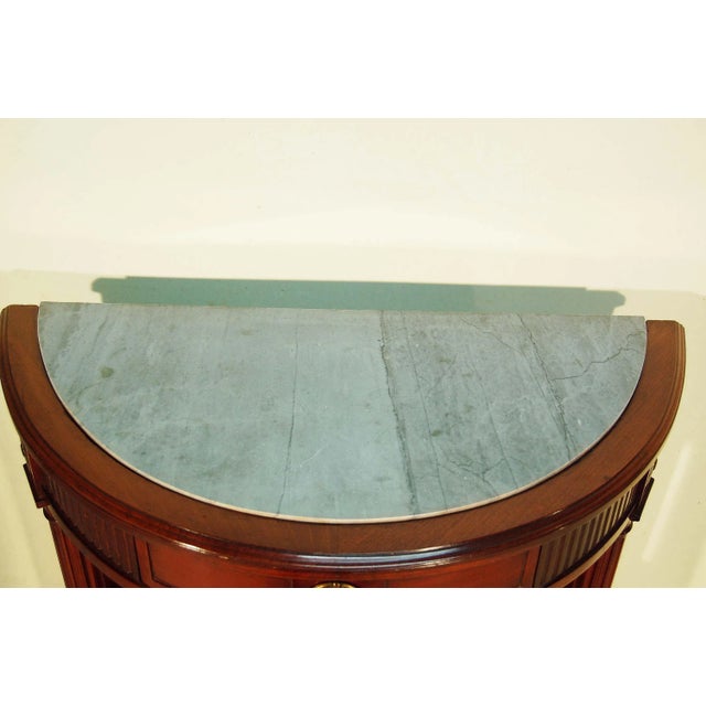 - Half-moon console table - Louis XVI style - Solid mahogany and mahogany veneer - Grooved belt opening with a molded...